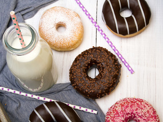 Bottle of milk and colorful donuts with chocolate and icing, selective focus