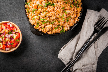 Mexican, Latin American cuisine. Mexican Rice and Beans Bowl- recipe made with rice and white beans, homemade, with fresh herbs and herbs. In a frying pan for cooking, with salsa, top view copy space