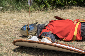 Medieval knight fallen in battle, with an arrow piercing his helmet and striking his head,...