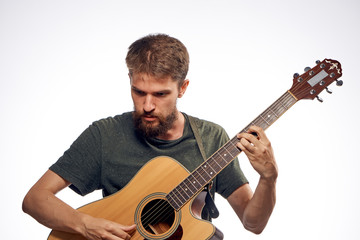 Young guy with a beard on a light background playing the guitar