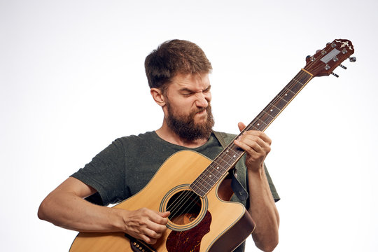 Young guy with a beard on a light background playing the guitar