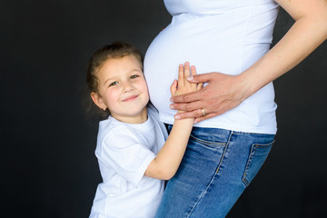 image of pregnant woman with their daughter hugging the tummy of pregnant mother