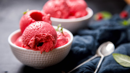 Ice cream Raspberry  in white bowl on the black background.Dessert.Copy space for Text.Sorbet In the form of a ball.selective focus. - obrazy, fototapety, plakaty