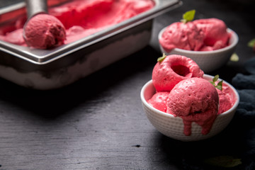 Ice cream Raspberry  in white bowl on the black background.Dessert.Copy space for Text.Sorbet In the form of a ball.selective focus.