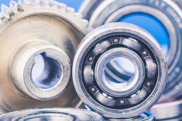 Group of various ball bearings and gears close up on nice blue background with reflections