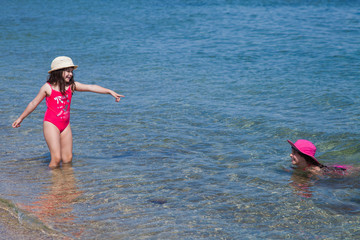 two girls in red bathing suits playing in the clear blue water