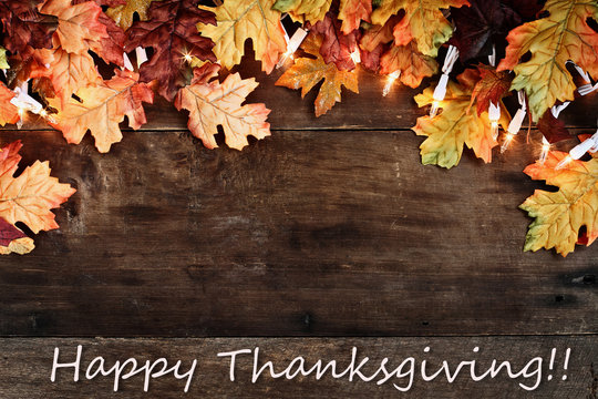 Fall Leaves and Text Happy Thanksgiving over Wooden Background