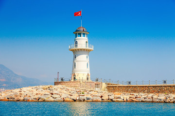 Fototapeta na wymiar Lighthouse in Alanya, Antalya district, Turkey, Asia. View on city from boat. Popular tourist destination. Clear water in sunny day.