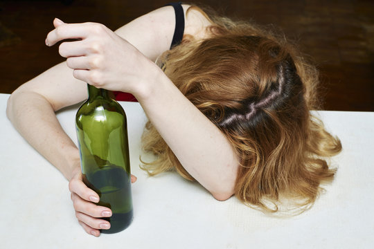 Drunk woman with bottle of wine, asleep at the table.Women's alcohol dependence.