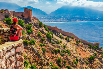 Young tourist woman look at ruins in Alanya peninsula, Antalya district, Turkey, Asia. Famous tourist destination with high mountains. Part of ancient old Castle. Summer bright day