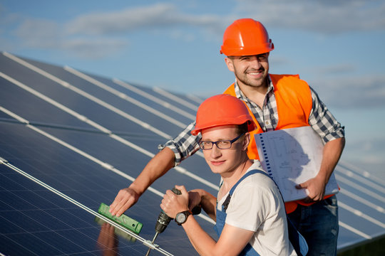 Engineers installing solar panels. Workers with tools maintaining photovoltaic panels.