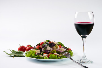 Fresh green organic salad with chicken meat and red dry wine isolated on white background with copy space.