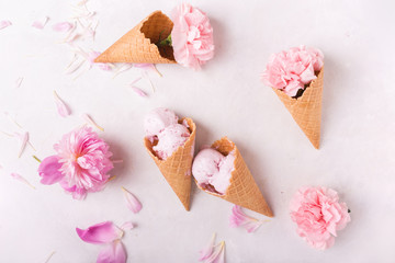 Ice cream in a waffle cone on a light background. Strawberry ice cream. Flowers in a waffle cone. Pink carnations. Flowers on a wooden  background. Copyspace. Flower photo concept.