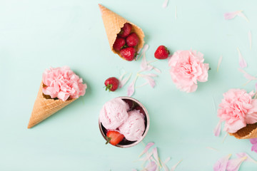 Ice cream in a waffle cone on a turquoise  background. Strawberry ice cream. Flowers in a waffle cone. Pink carnations. Flowers on a wooden  background. Copyspace. Flower photo concept.