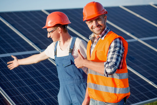 Foreman and employee at solar energy station. Foreman showing thumb up and looking in camera.