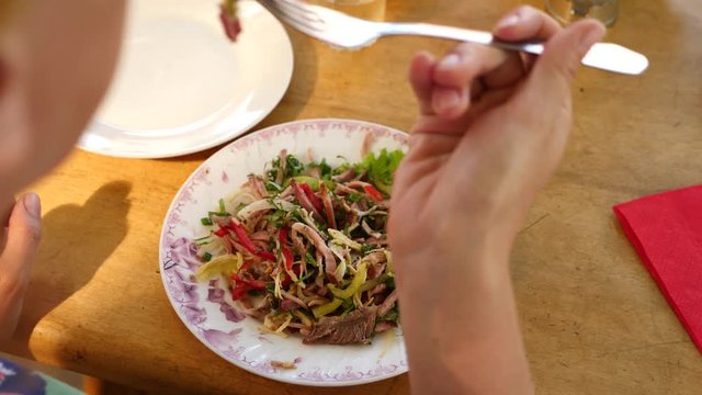 Someone eats meat salad with a fork and a knife. close-up. Slow motion.