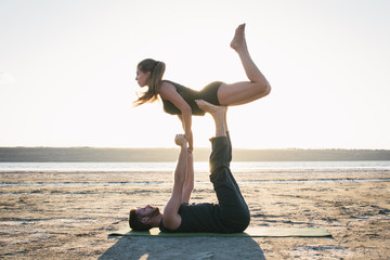 Young couple practicing yoga on beach at sunrise or sunset © sashafolly