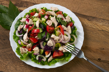 Fresh salad with fresh vegetables and chicken meat on old rustic wooden table, healthy food concept