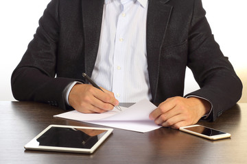 Businessman signs business paper agreement contract at desk in office of company isolated on white background