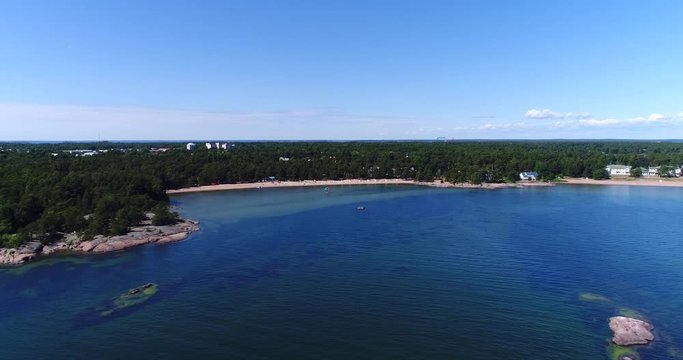Hanko beach, Cinema 4k aerial view towards plagen beach, out from the turquoise sea, on hango regatta day, in the finnish archipelago of Hanko, Finland