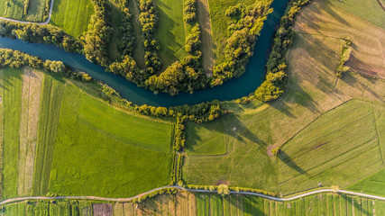 River bend surrounded by fields from bird's eye view.