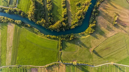 Foto auf Acrylglas River bend surrounded by fields from bird's eye view. © anzebizjan