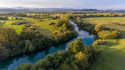 Fototapeta na wymiar Aerial view of river bending across fields at sunset.
