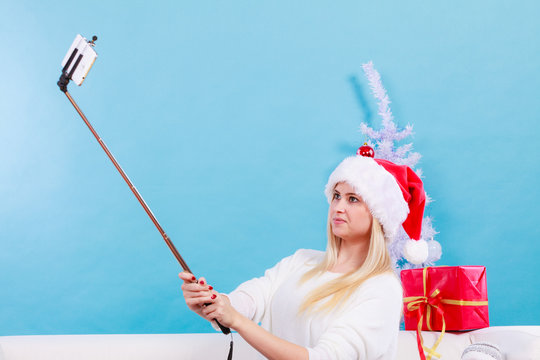 Girl in santa hat taking picture of herself using selfie stick