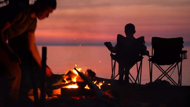 Father with child are Sitting near Campfire at Night.