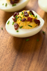 Deviled egg with bacon and chives, photographed with natural light (Selective Focus, Focus on the front of the egg yolk)