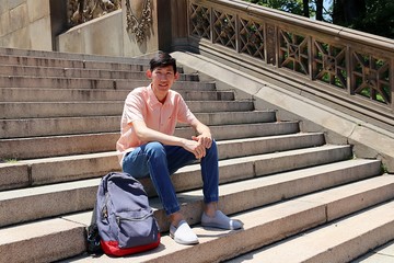 Young attractive asian student sitting on outdoor steps