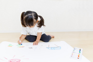 フローリングで絵を描く幼い女の子