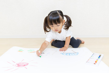 フローリングで絵を描く幼い女の子