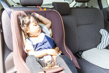 チャイルドシートで寝る幼い女の子