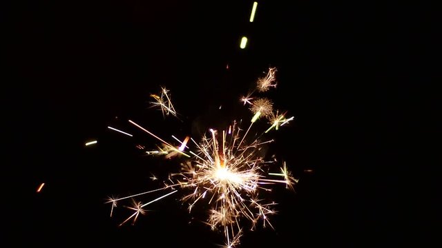 Slow Mo. Burning Sparkler floating in the air on black background. Loop. Bengal fire a type of stick with the thick paste of metallic fuel, produces tiny glowing sparks that shoot off in all direction