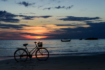 Fototapeta premium Bicycle and boat at sunset on bay of Bengal