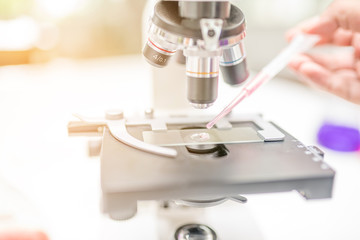 Microscope on the table in laboratory room with laboratory equipment