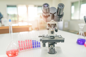 Microscope on the table in laboratory room with laboratory equipment