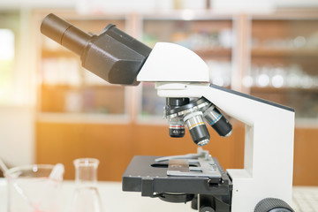 Microscope on the table in laboratory room with laboratory equipment