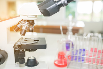 Microscope on the table in laboratory room with laboratory equipment
