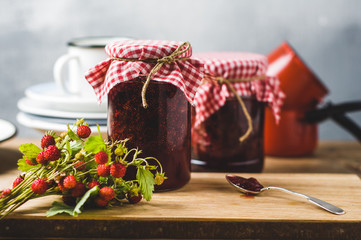 Homemade strawberry jam in jars and inredients on a wooden cutting board