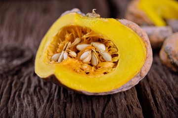 cut raw pumpkin with seed on wooden background
