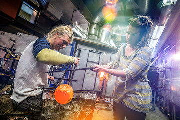 Two Blowing Glass Artists Finishing a Piece.