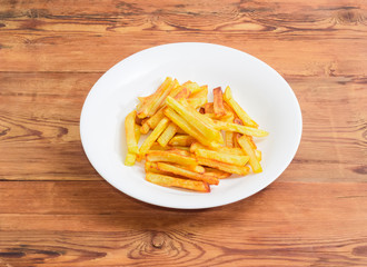 French fries on the white dish on a wooden surface