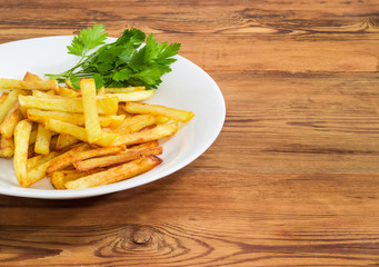 French fries on the white dish on a wooden surface