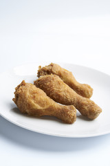 a white plate with fried chicken drumsticks 
