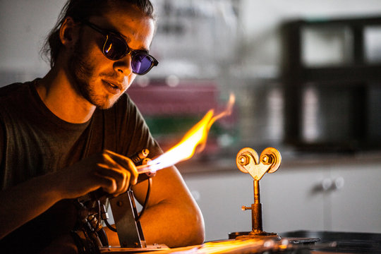 Glassblowing Young Man Working on a Torch Flame with Glass Tubes