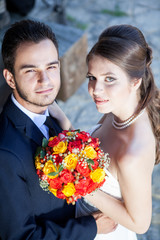 Wife and groom in wedding day looking up at the camera. Just married couple