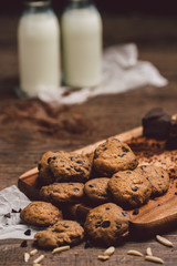 Chocolate cookies , mike on  wooden table. Chocolate chip cookies shot on coffee colored cloth, closeup.