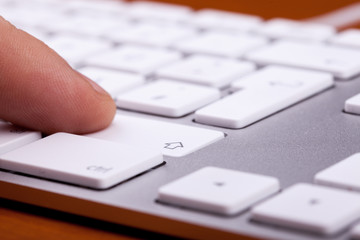 Finger pressing on keyboard key in close up